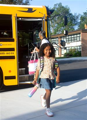 girl walks from bus smiling