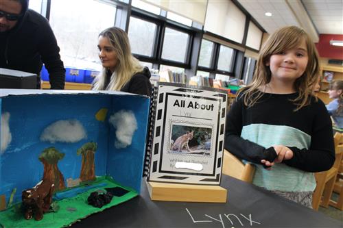 Girl stands next to her writing project