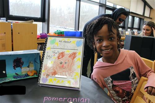 Girl smiling next to book she made