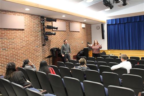 Woman talking to crowd in auditorium