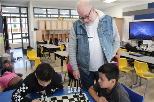 Man watching as kids play chess