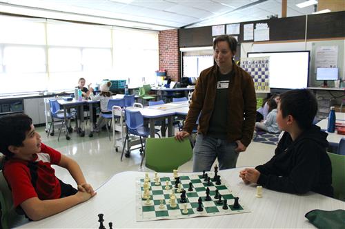 Woman talking to kids playing chess