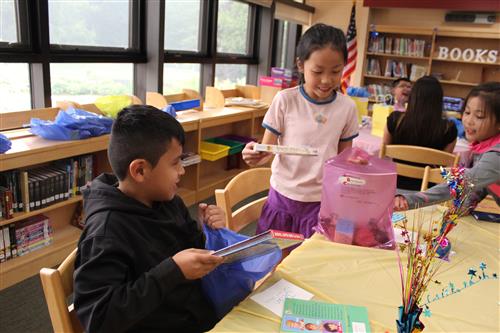 Two kids at table looking at books