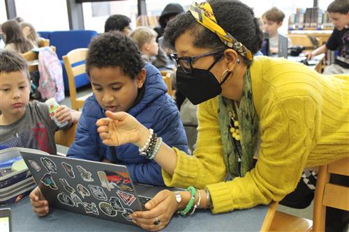 Women helps boy on computer